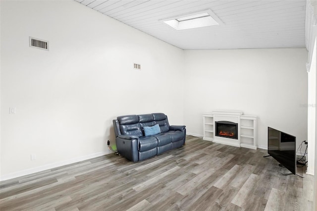 living area featuring high vaulted ceiling, hardwood / wood-style flooring, and a skylight