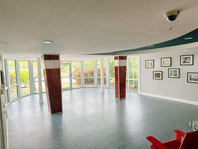 interior space featuring ornate columns, floor to ceiling windows, and a textured ceiling