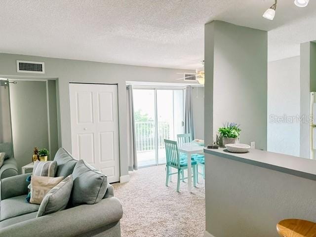 carpeted living room featuring ceiling fan and a textured ceiling