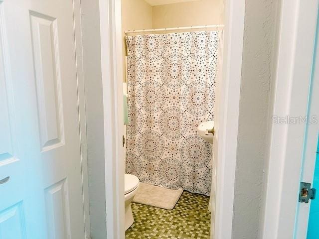 bathroom with a shower with curtain and toilet