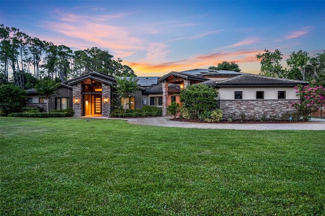 view of front of property featuring solar panels and a yard