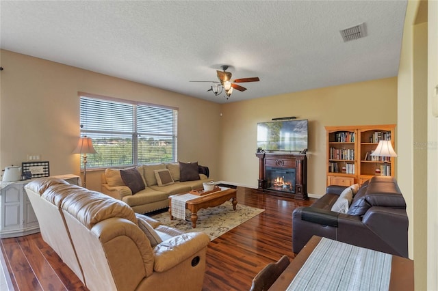 living room with ceiling fan, a textured ceiling, and dark hardwood / wood-style floors