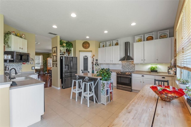 kitchen featuring decorative backsplash, appliances with stainless steel finishes, wall chimney range hood, and white cabinetry