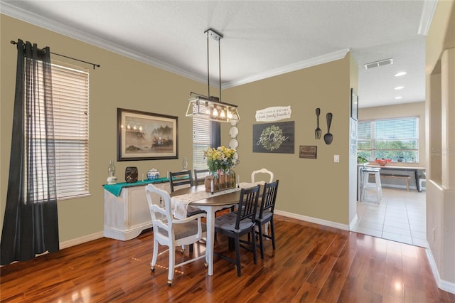 dining room with a textured ceiling, dark hardwood / wood-style floors, and ornamental molding