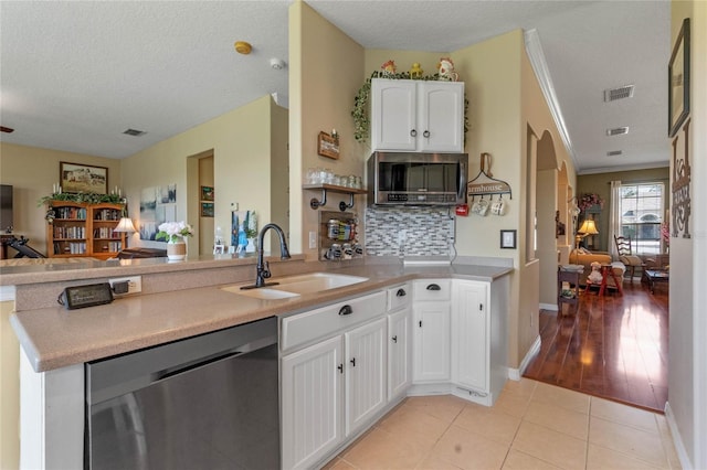 kitchen with stainless steel dishwasher, sink, white cabinetry, a textured ceiling, and light tile patterned floors