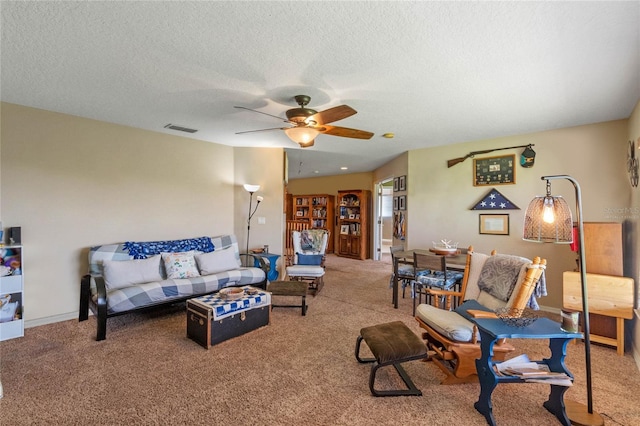 carpeted living room with ceiling fan and a textured ceiling