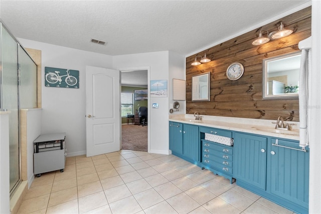 bathroom with wooden walls, tile patterned flooring, walk in shower, a textured ceiling, and vanity