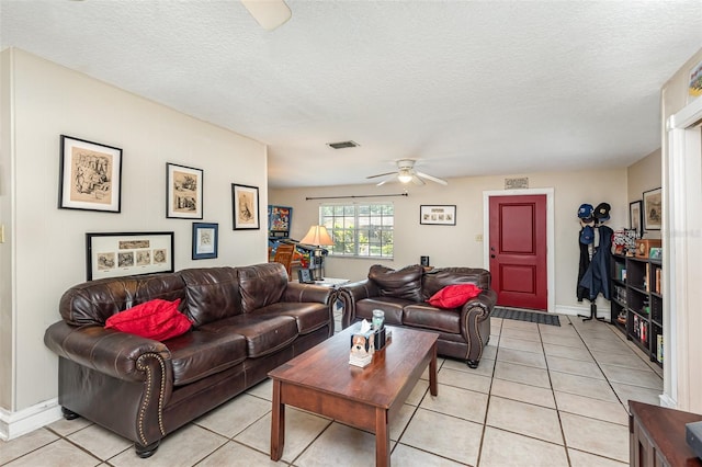 living room featuring ceiling fan, light tile patterned floors, and a textured ceiling