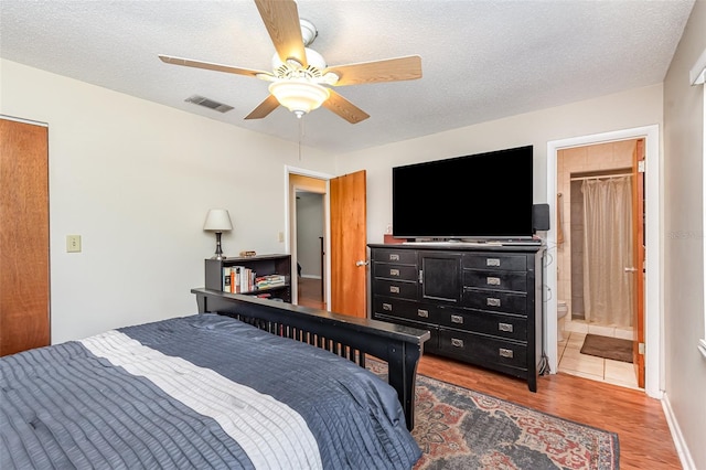 bedroom featuring hardwood / wood-style floors, a textured ceiling, ensuite bath, and ceiling fan