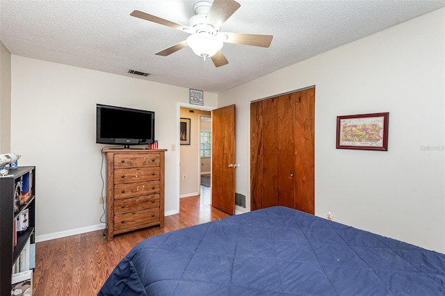 bedroom with ceiling fan, wood-type flooring, a textured ceiling, and a closet