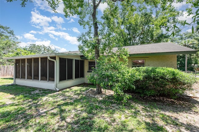 back of property with a lawn and a sunroom