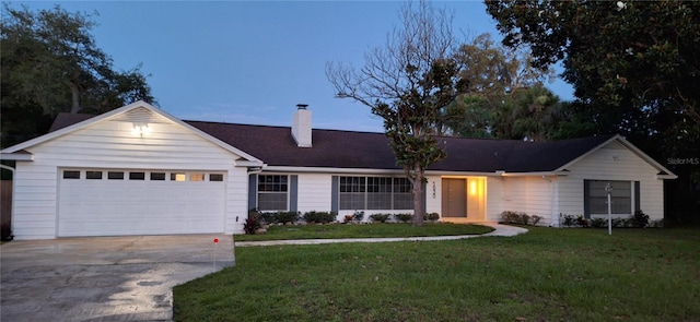 ranch-style home with a yard, a chimney, an attached garage, and driveway