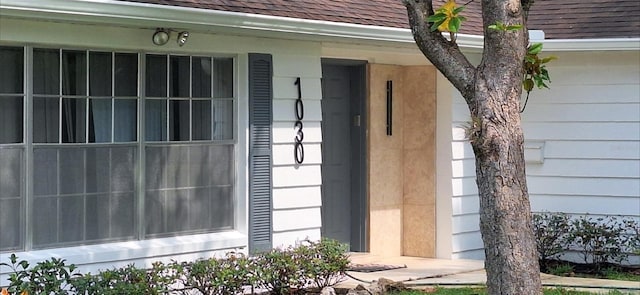 doorway to property with a shingled roof