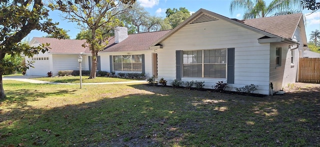 view of front of home with roof with shingles, a chimney, an attached garage, a front yard, and fence