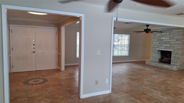 tiled foyer entrance featuring a fireplace, crown molding, and ceiling fan