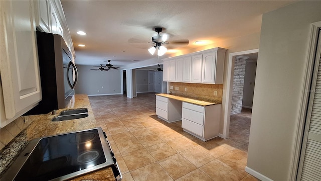 kitchen with stove, tasteful backsplash, white cabinets, light tile patterned floors, and ceiling fan