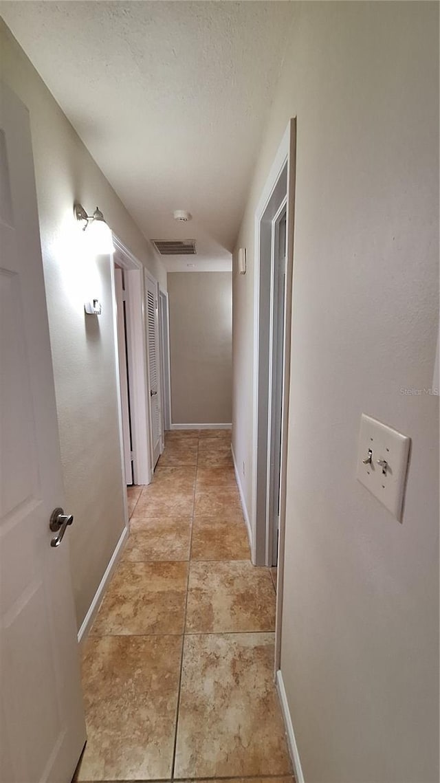 hallway with baseboards and a textured ceiling