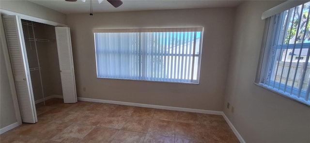 unfurnished bedroom with tile patterned floors, multiple windows, a closet, and ceiling fan