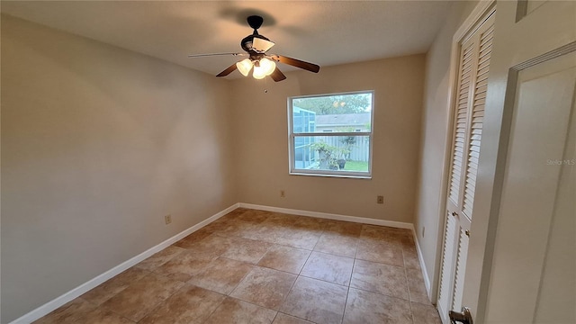 unfurnished bedroom featuring a closet, light tile patterned flooring, a ceiling fan, and baseboards