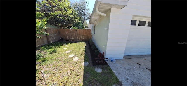 view of property exterior featuring a garage, fence, and a lawn