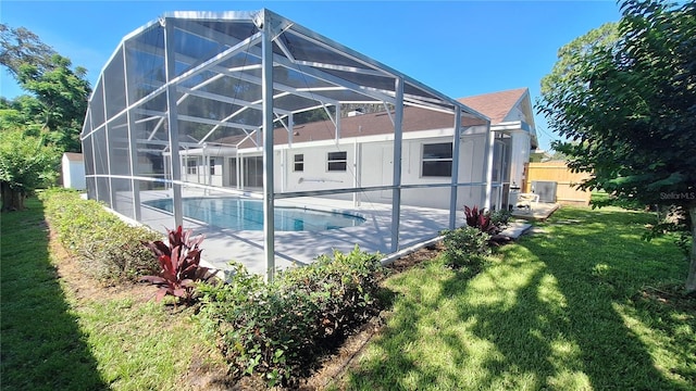 pool featuring cooling unit, glass enclosure, a yard, and a patio