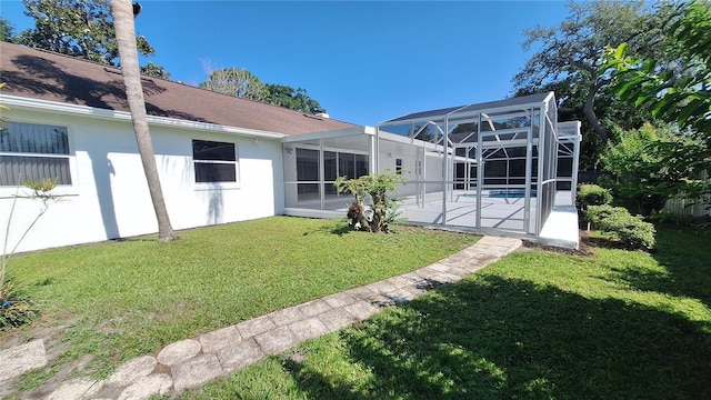 rear view of property featuring a lanai, an outdoor pool, a lawn, and stucco siding