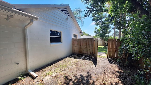 view of side of home featuring concrete block siding and fence