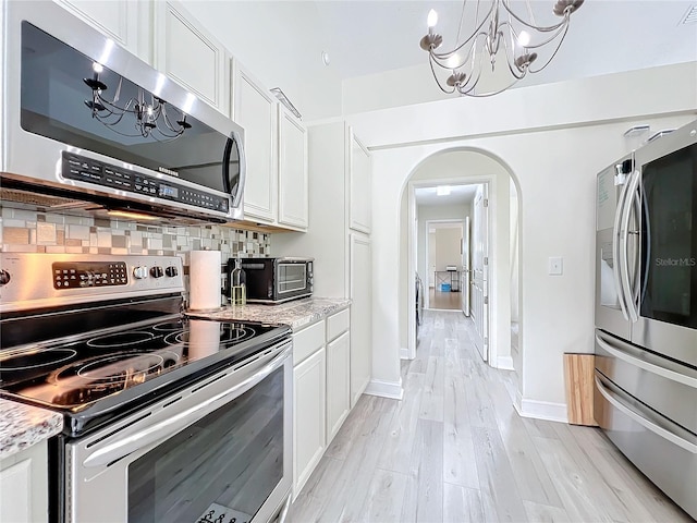 kitchen with light stone counters, white cabinetry, stainless steel appliances, and tasteful backsplash