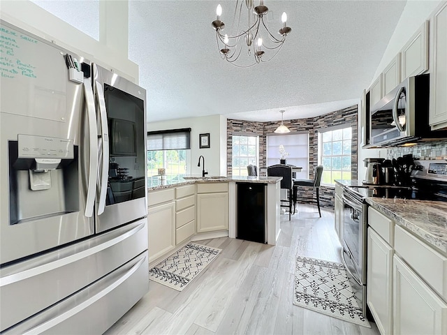 kitchen with appliances with stainless steel finishes, a textured ceiling, pendant lighting, and a healthy amount of sunlight