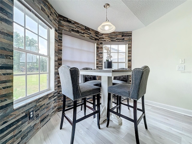 dining space with wood-type flooring, a textured ceiling, and plenty of natural light