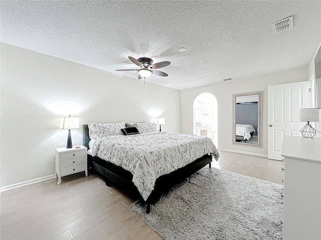 bedroom with ceiling fan, light hardwood / wood-style floors, and a textured ceiling