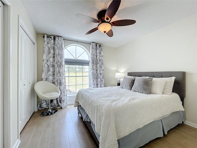 bedroom with a closet, ceiling fan, hardwood / wood-style floors, and a textured ceiling