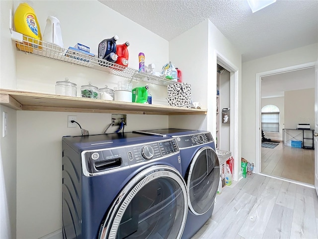 laundry area with washer and clothes dryer, light hardwood / wood-style flooring, and a textured ceiling