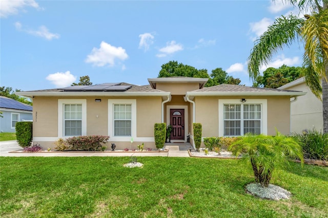 view of front of home with a front yard and solar panels