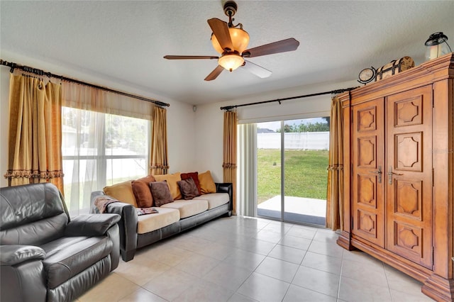 living room with a textured ceiling, light tile flooring, and ceiling fan