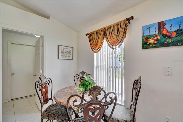 dining room featuring vaulted ceiling and light tile floors