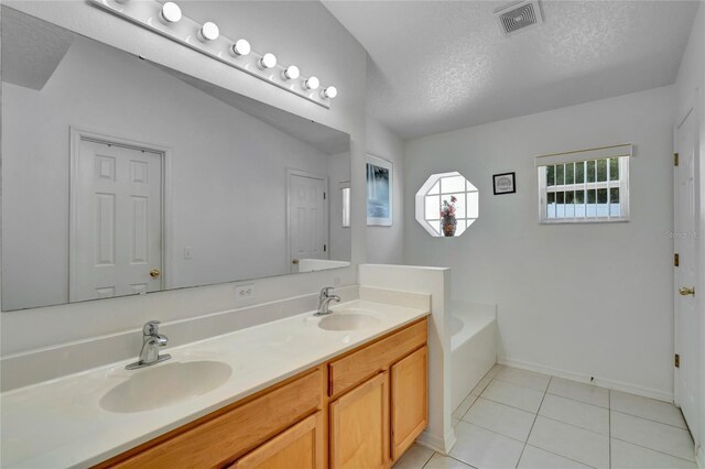 bathroom with vaulted ceiling, double sink vanity, a bathtub, a textured ceiling, and tile floors