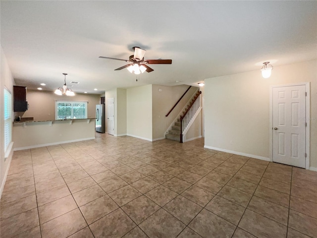 unfurnished living room featuring ceiling fan with notable chandelier and light tile patterned flooring