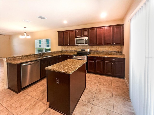 kitchen with a center island, kitchen peninsula, a chandelier, pendant lighting, and appliances with stainless steel finishes