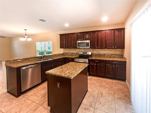 kitchen with kitchen peninsula, plenty of natural light, pendant lighting, and appliances with stainless steel finishes