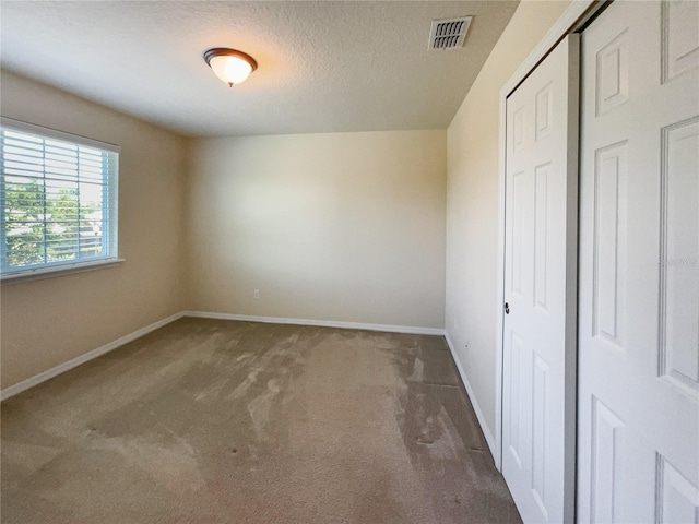 unfurnished bedroom featuring dark colored carpet, a textured ceiling, and a closet