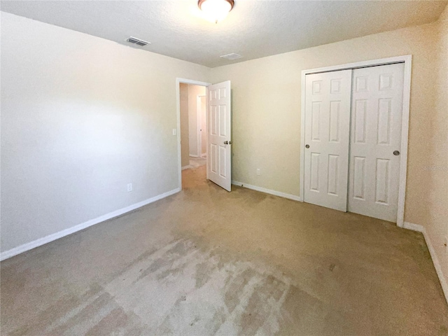 unfurnished bedroom with light carpet and a closet