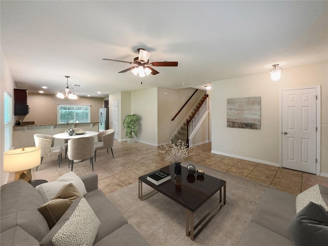 tiled living room with ceiling fan with notable chandelier