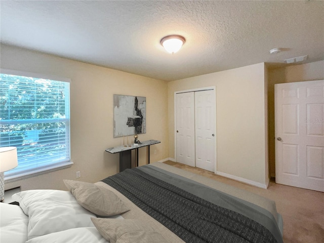 carpeted bedroom with a closet and a textured ceiling