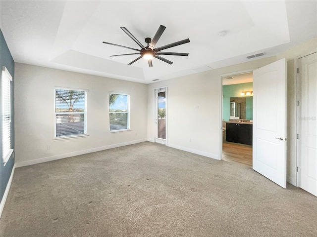 unfurnished room featuring ceiling fan, a raised ceiling, and carpet floors