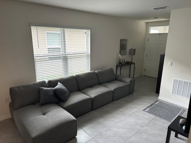 tiled living room featuring a textured ceiling