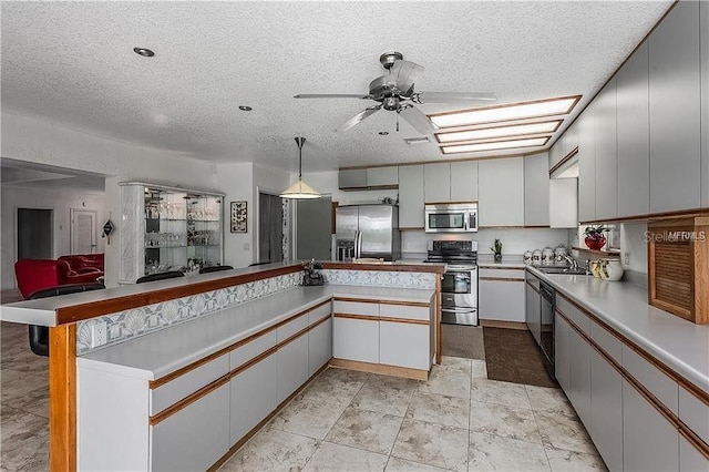 kitchen with appliances with stainless steel finishes, kitchen peninsula, hanging light fixtures, and white cabinets