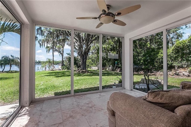 sunroom / solarium with a water view and ceiling fan