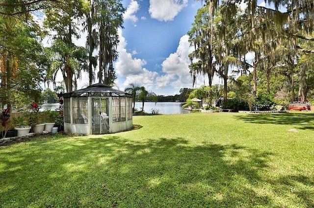 view of yard with a greenhouse, an outdoor structure, and a water view