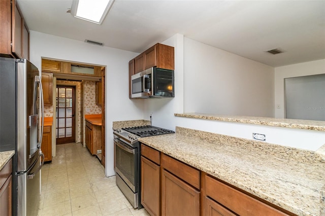 kitchen featuring light tile patterned floors, appliances with stainless steel finishes, and light stone countertops